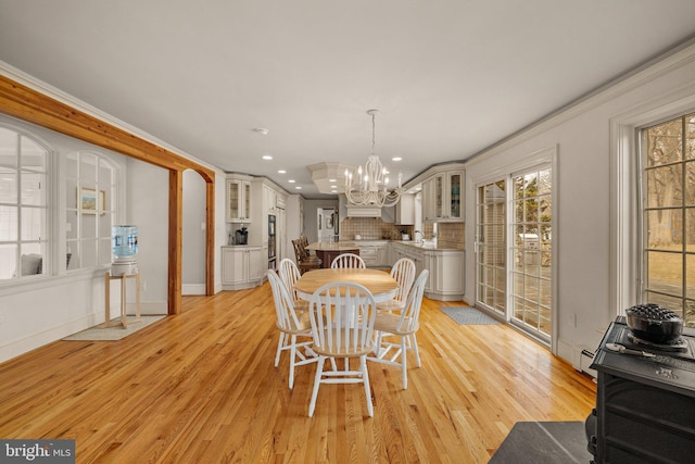 dining area with light wood-style flooring, recessed lighting, crown molding, baseboards, and an inviting chandelier