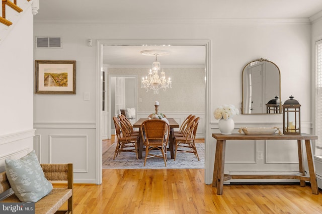 dining area featuring a wainscoted wall, crown molding, visible vents, an inviting chandelier, and light wood-type flooring