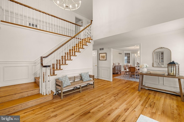 foyer entrance with visible vents, stairway, a notable chandelier, and wood finished floors