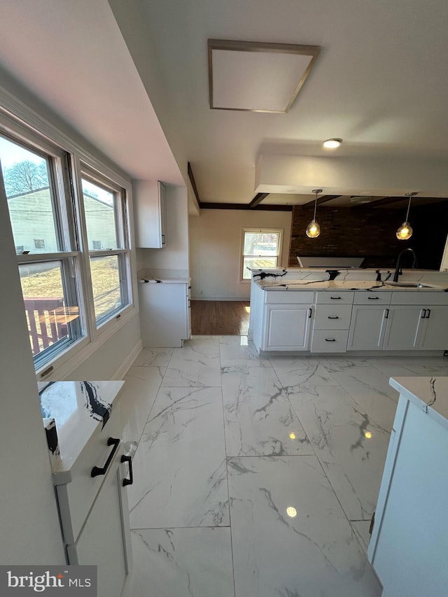 kitchen featuring baseboards, white cabinets, marble finish floor, light countertops, and a sink