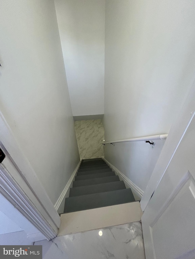 staircase with marble finish floor and baseboards