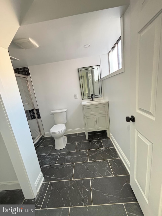 bathroom with toilet, vanity, baseboards, marble finish floor, and a shower stall