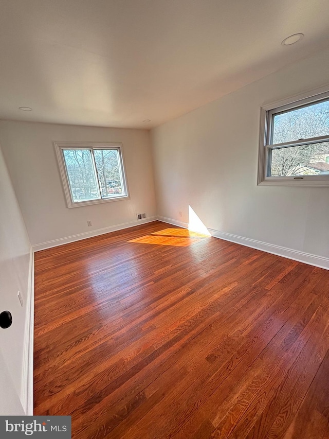 spare room featuring visible vents, baseboards, and wood finished floors