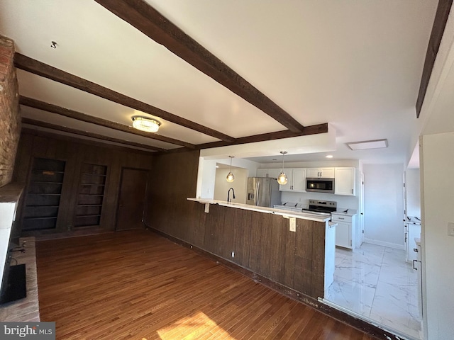 kitchen featuring appliances with stainless steel finishes, a breakfast bar, a peninsula, light countertops, and white cabinetry