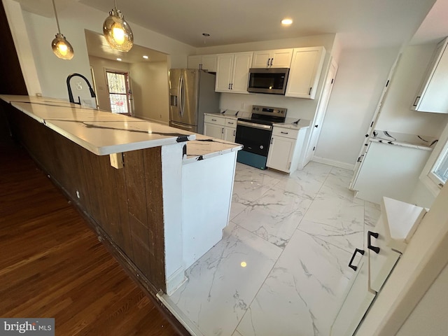 kitchen with appliances with stainless steel finishes, a peninsula, marble finish floor, light countertops, and white cabinetry