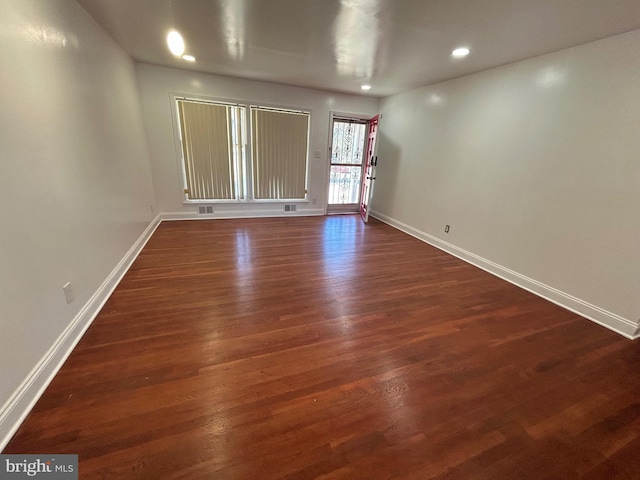 spare room featuring recessed lighting, dark wood finished floors, and baseboards