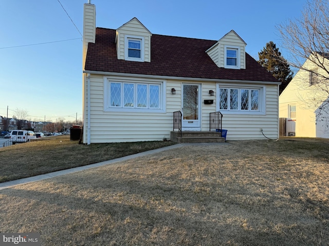 cape cod home with a front yard and a chimney