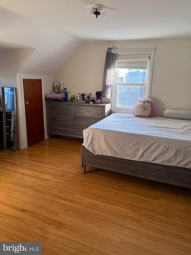 bedroom featuring light wood-type flooring and vaulted ceiling