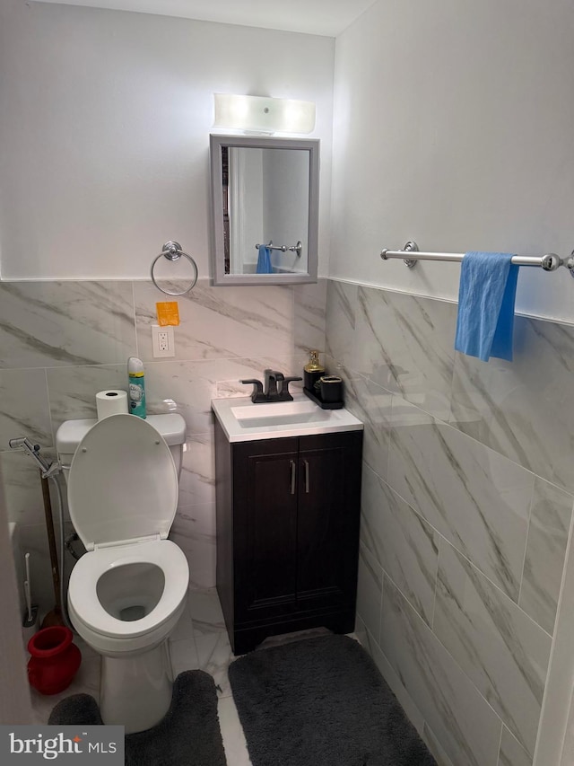 half bath featuring toilet, marble finish floor, a wainscoted wall, and vanity