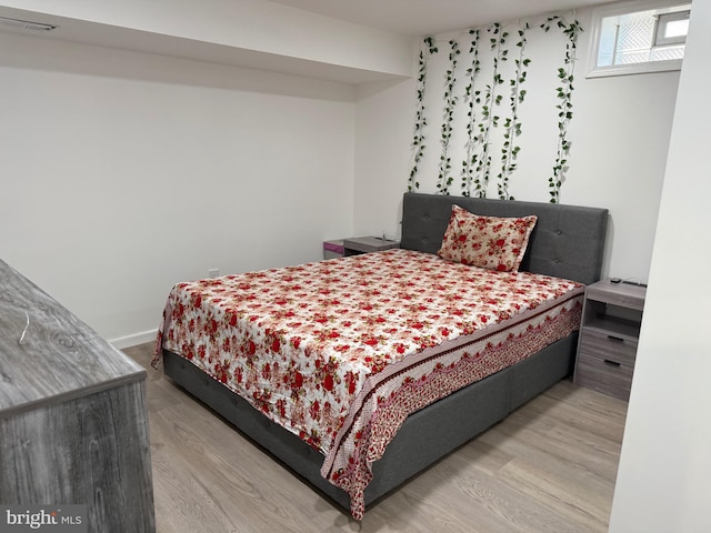 bedroom featuring baseboards, visible vents, and wood finished floors