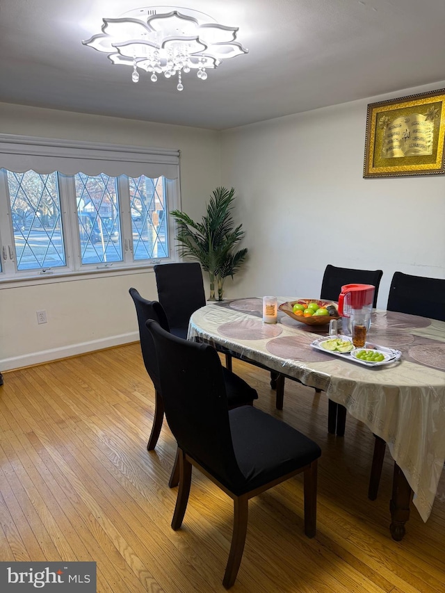 dining area featuring light wood-style flooring, baseboards, and a notable chandelier