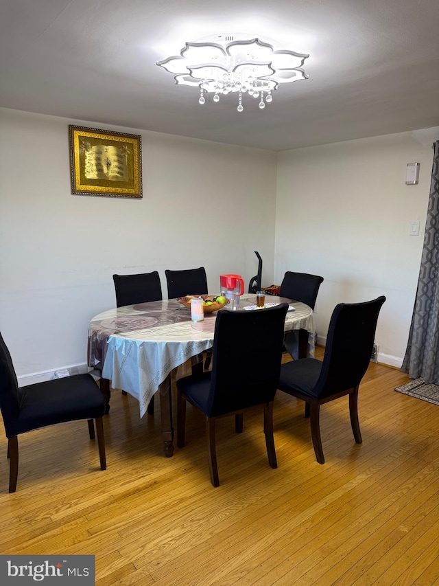 dining space featuring light wood-style floors, a notable chandelier, and baseboards