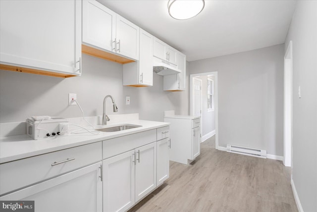 kitchen featuring light wood-style flooring, a baseboard heating unit, a sink, white cabinetry, and light countertops