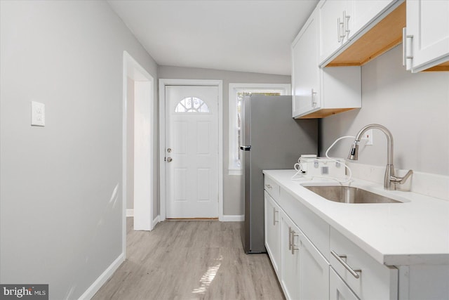 washroom featuring a sink, light wood-style flooring, and baseboards