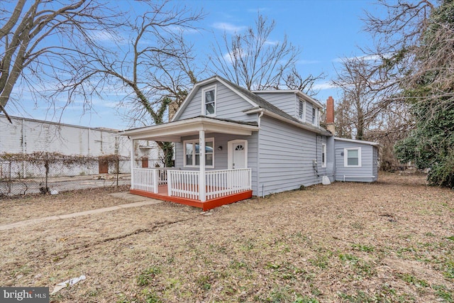 view of front of property featuring a porch, fence, and a chimney