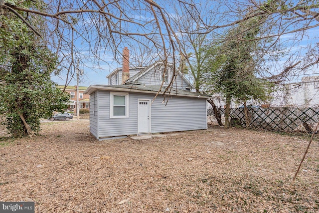 back of property with an outbuilding, fence, and a chimney