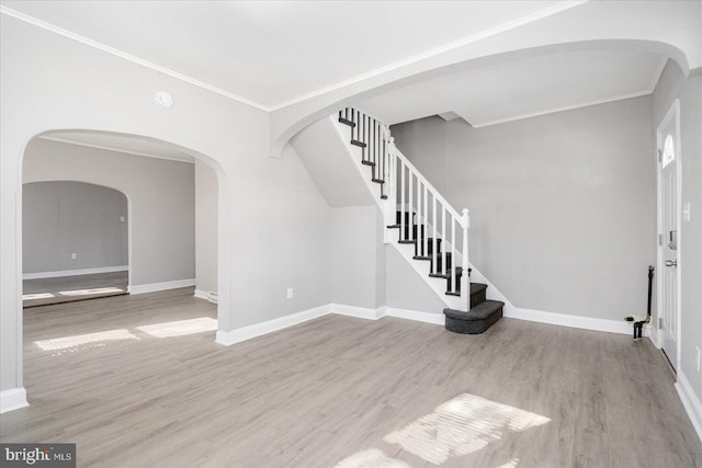 foyer entrance with stairs, ornamental molding, baseboards, and wood finished floors