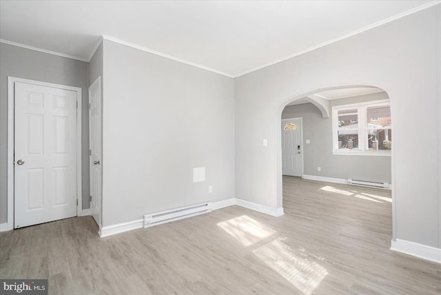 spare room with a baseboard heating unit, wood finished floors, and arched walkways