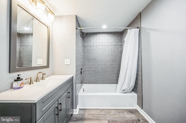 bathroom with shower / bath combo with shower curtain, vanity, baseboards, and wood finished floors