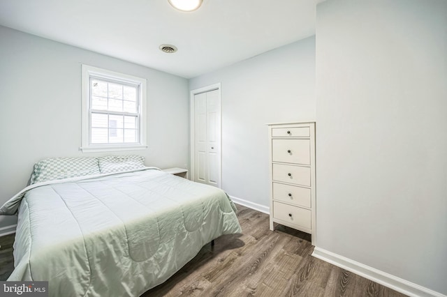 bedroom with baseboards, a closet, visible vents, and wood finished floors