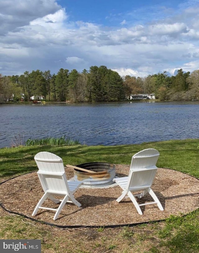 view of yard featuring a forest view, an outdoor fire pit, and a water view