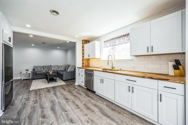 kitchen featuring butcher block counters, refrigerator, a sink, light wood-type flooring, and stainless steel dishwasher