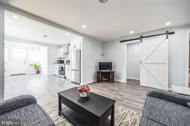 living area featuring light wood-type flooring, baseboards, recessed lighting, and a barn door