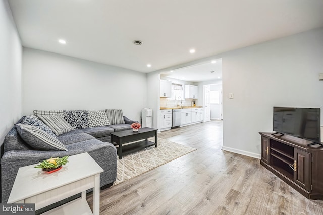 living room featuring light wood-style floors, recessed lighting, visible vents, and baseboards