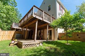 back of house with fence private yard, a yard, and a wooden deck