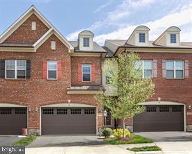 multi unit property featuring brick siding, driveway, and an attached garage