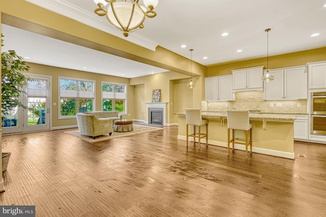 kitchen with open floor plan, backsplash, a glass covered fireplace, and light wood-style floors