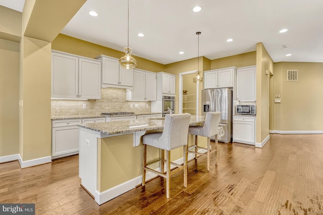 kitchen with tasteful backsplash, visible vents, light wood-style flooring, stainless steel appliances, and white cabinetry