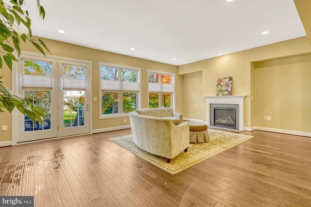 unfurnished room featuring recessed lighting, baseboards, wood finished floors, and a glass covered fireplace