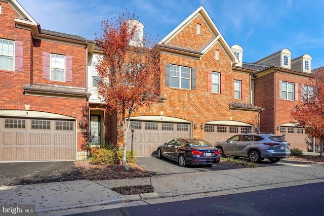 townhome / multi-family property featuring a garage, brick siding, and driveway