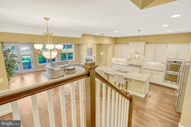 interior space with stainless steel gas cooktop, a fireplace, light stone countertops, light wood finished floors, and tasteful backsplash