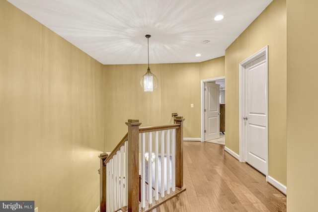 hallway with recessed lighting, baseboards, an upstairs landing, and wood finished floors