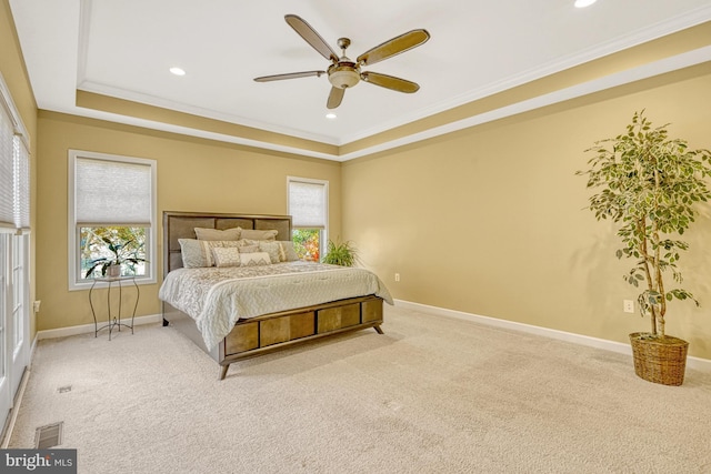 carpeted bedroom with baseboards, multiple windows, a tray ceiling, and ornamental molding