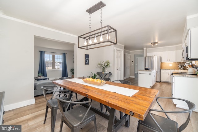 dining room with baseboards, crown molding, and light wood finished floors