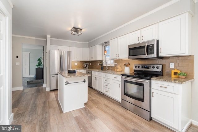 kitchen with light wood finished floors, tasteful backsplash, a kitchen island, appliances with stainless steel finishes, and white cabinetry