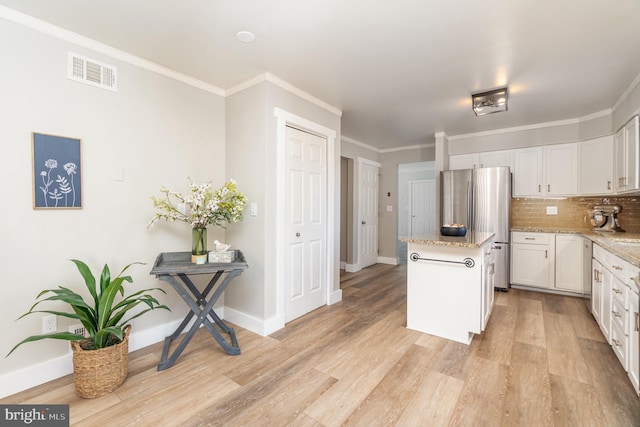 kitchen with visible vents, light wood-style flooring, freestanding refrigerator, and a center island