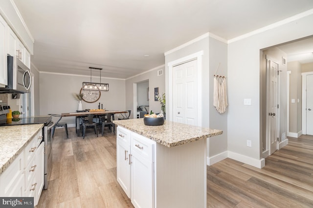 kitchen featuring light wood finished floors, appliances with stainless steel finishes, white cabinets, and crown molding