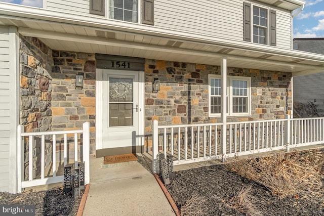 view of exterior entry with covered porch and stone siding