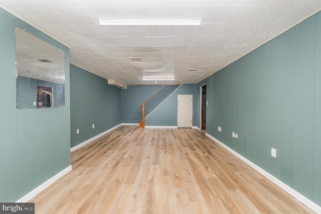 finished basement with stairs, wood finished floors, visible vents, and baseboards