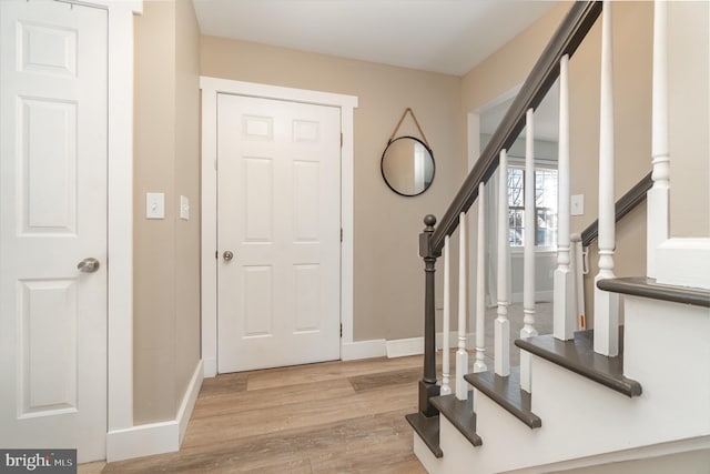 entryway featuring light wood-style floors, stairway, and baseboards