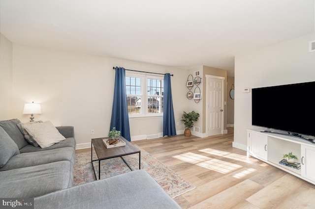 living area with light wood-style floors, visible vents, and baseboards