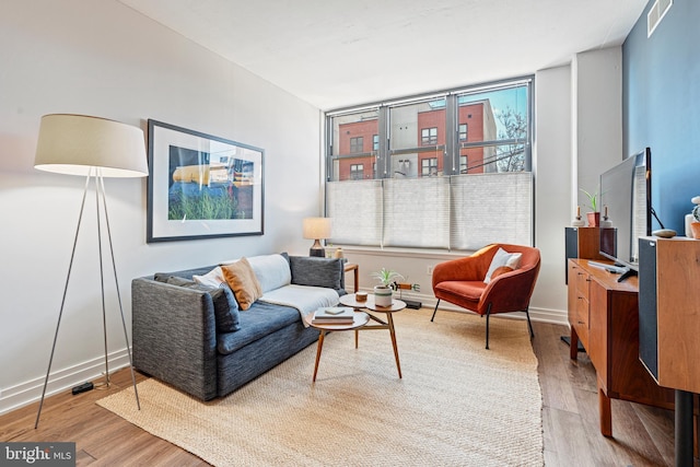 living room featuring baseboards, visible vents, and wood finished floors