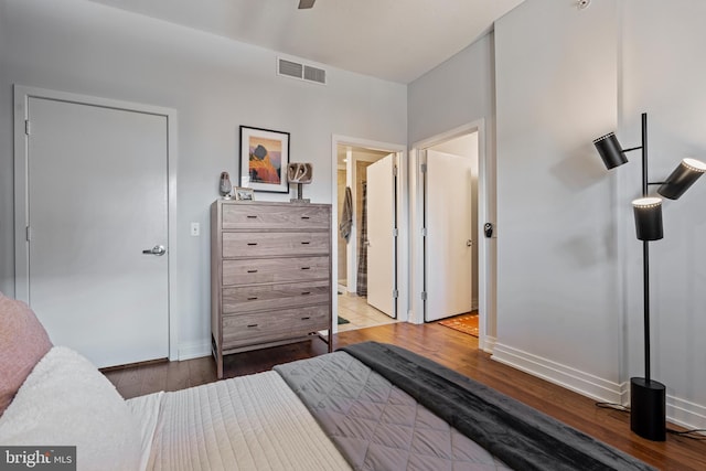 bedroom featuring a ceiling fan, visible vents, baseboards, and wood finished floors