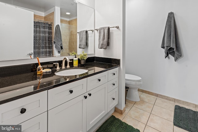 full bath featuring tile patterned flooring, toilet, vanity, baseboards, and tiled shower