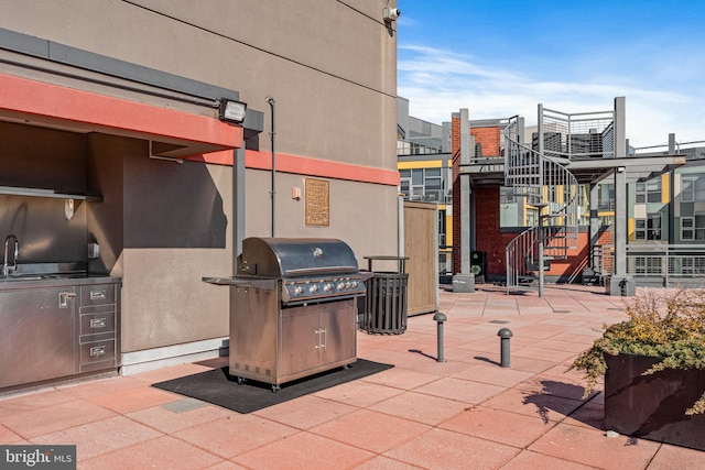 view of patio / terrace featuring stairway, a sink, grilling area, and an outdoor kitchen