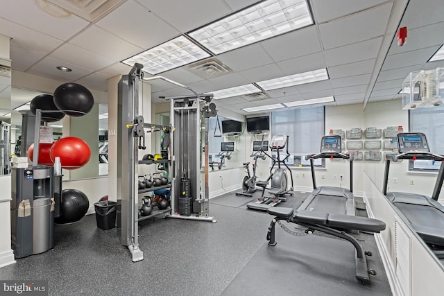 workout area featuring a drop ceiling, visible vents, and baseboards